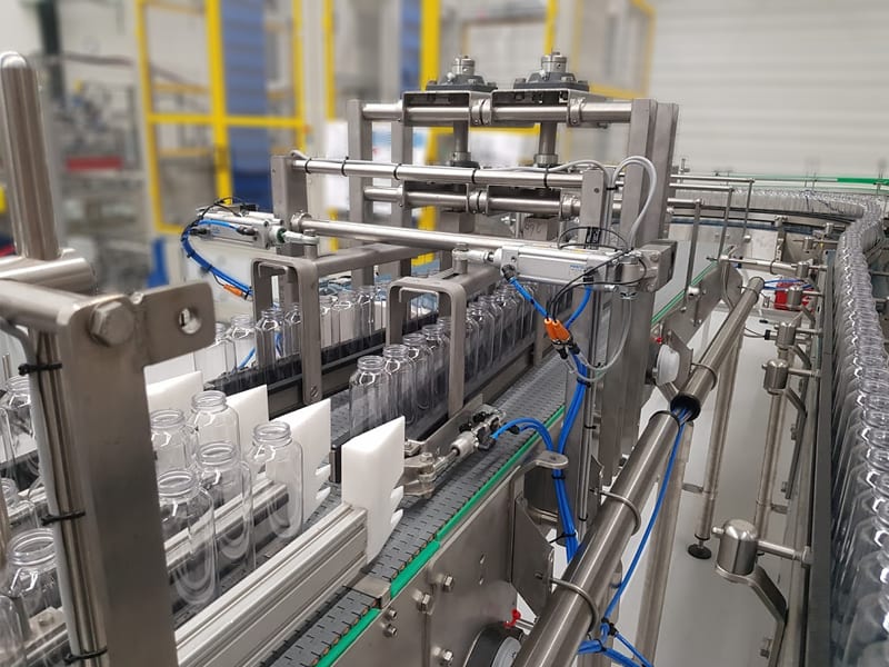 Geautomatiseerde productielijn met kleine lege flessen op lopende band.