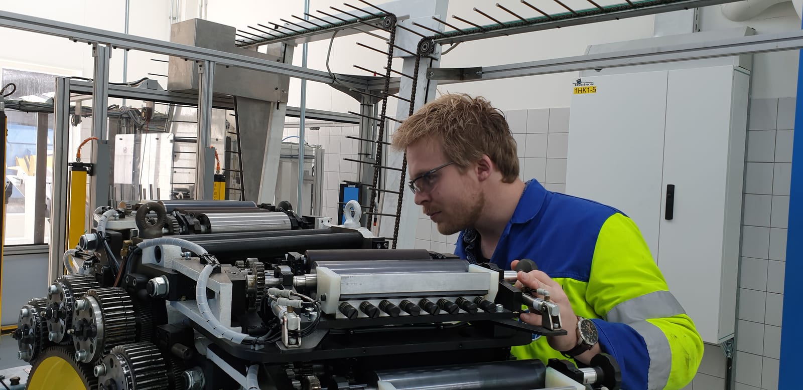 Monteur inspecteert machineonderdelen in een industriële omgeving.